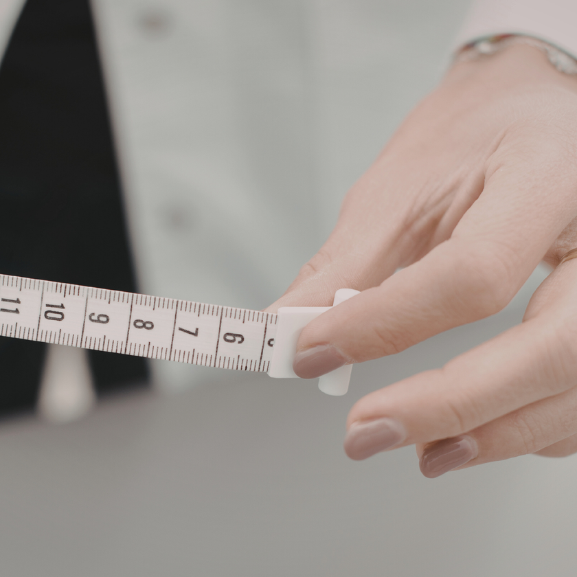 Hand holding a measuring tape against a blurred background