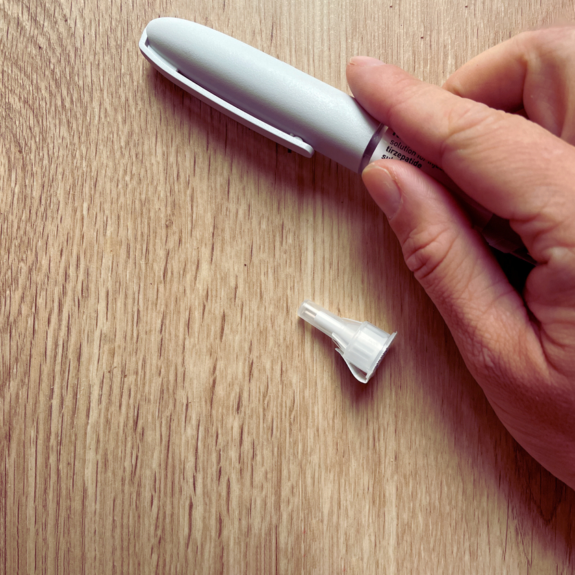 Hand holding a white electronic device on a wooden surface