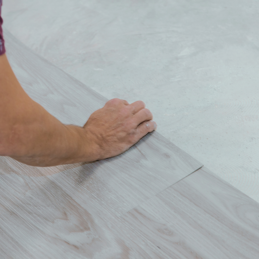 Person installing a piece of gray vinyl flooring